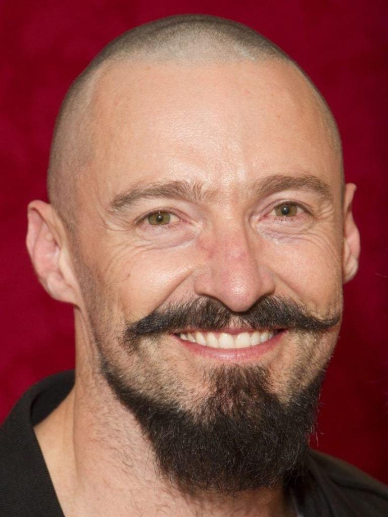 Hugh Jackman with a buzzcut and handlebar moustache.