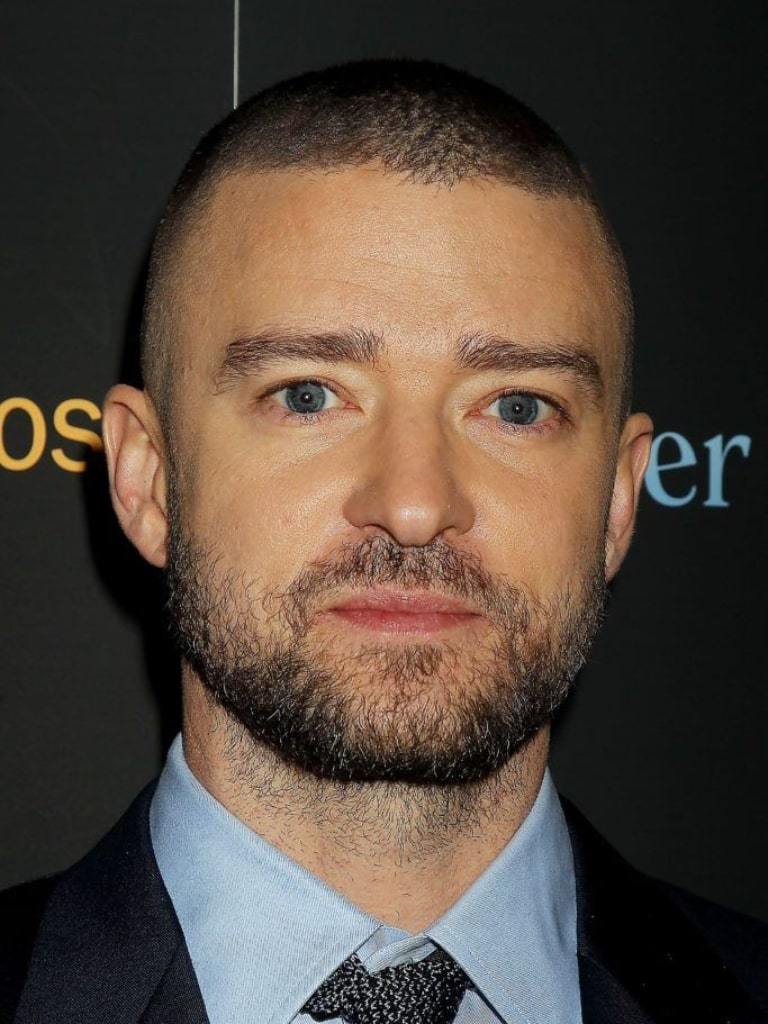 Justin Timberlake with a buzzcut hairstyle wearing a suit at an event.