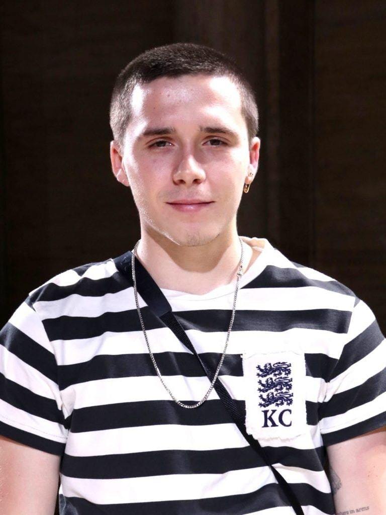 Brooklyn Beckham with a short buzzcut hairstyle wearing a black and white striped t-shirt.
