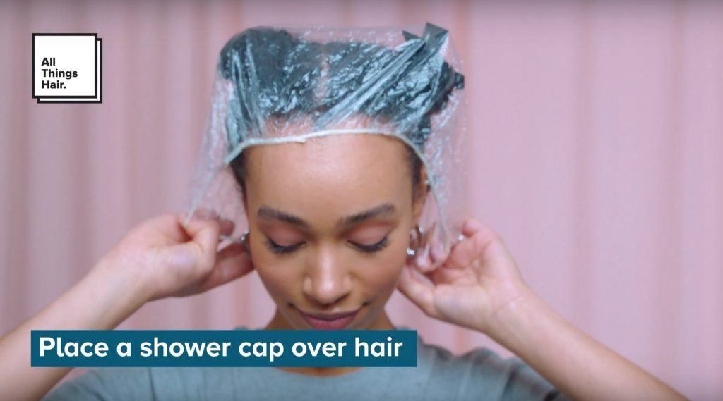 Natural haired woman putting a shower cap over her hair