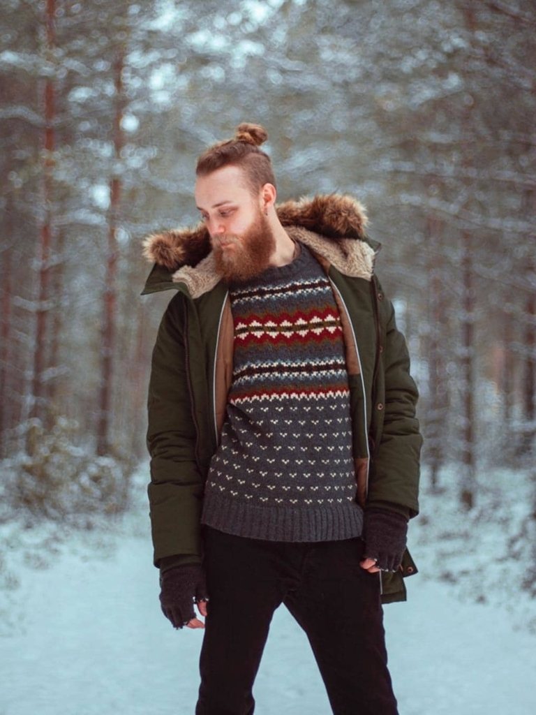 Ginger man with a braided man bun with shaved sides and a beard
