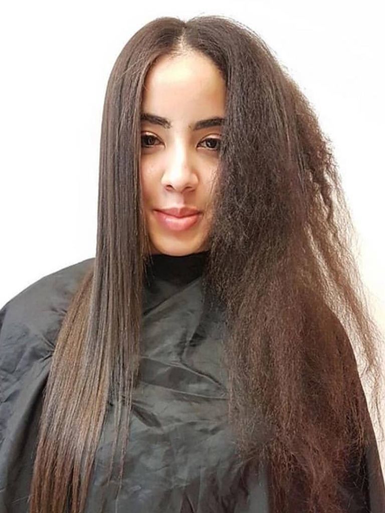 Woman in a salon getting a Japanese keratin hair treatment for curly hair.