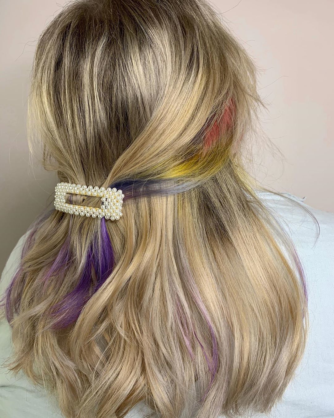 Woman with sandy blonde hair with a peekaboo rainbow streak
