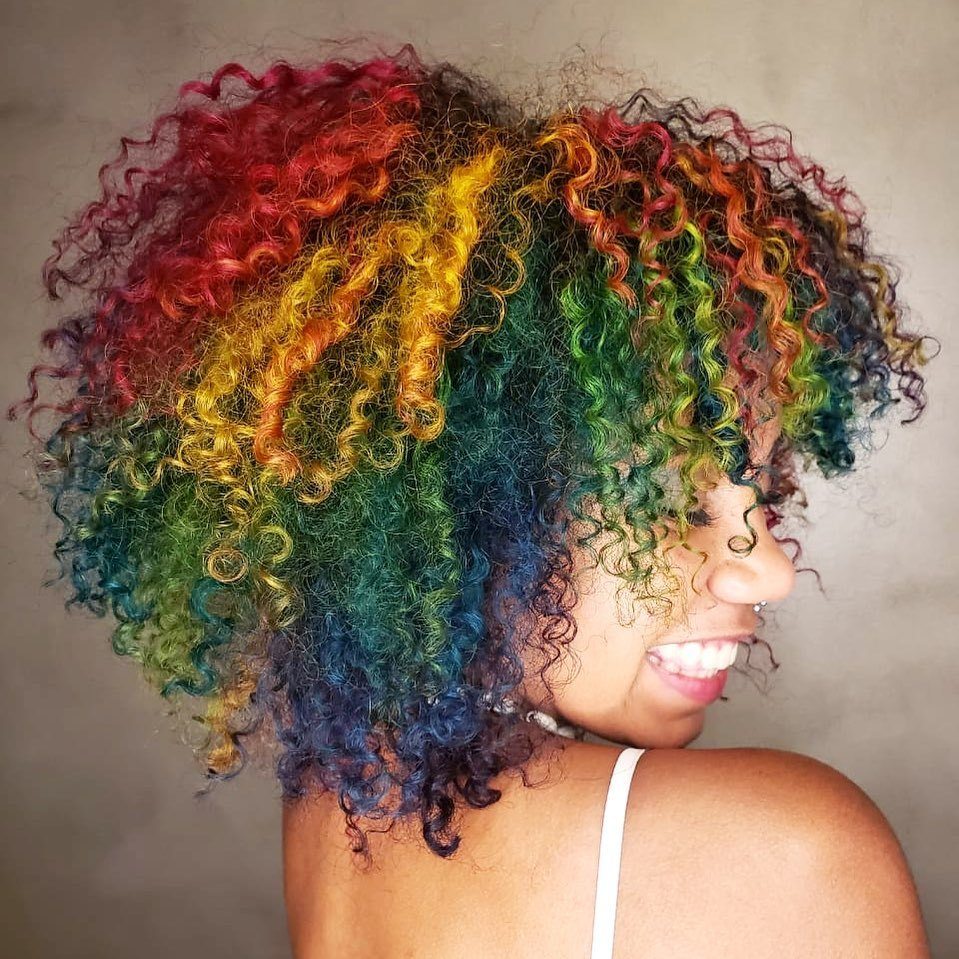 Woman with curly natural hair dyed rainbow colours