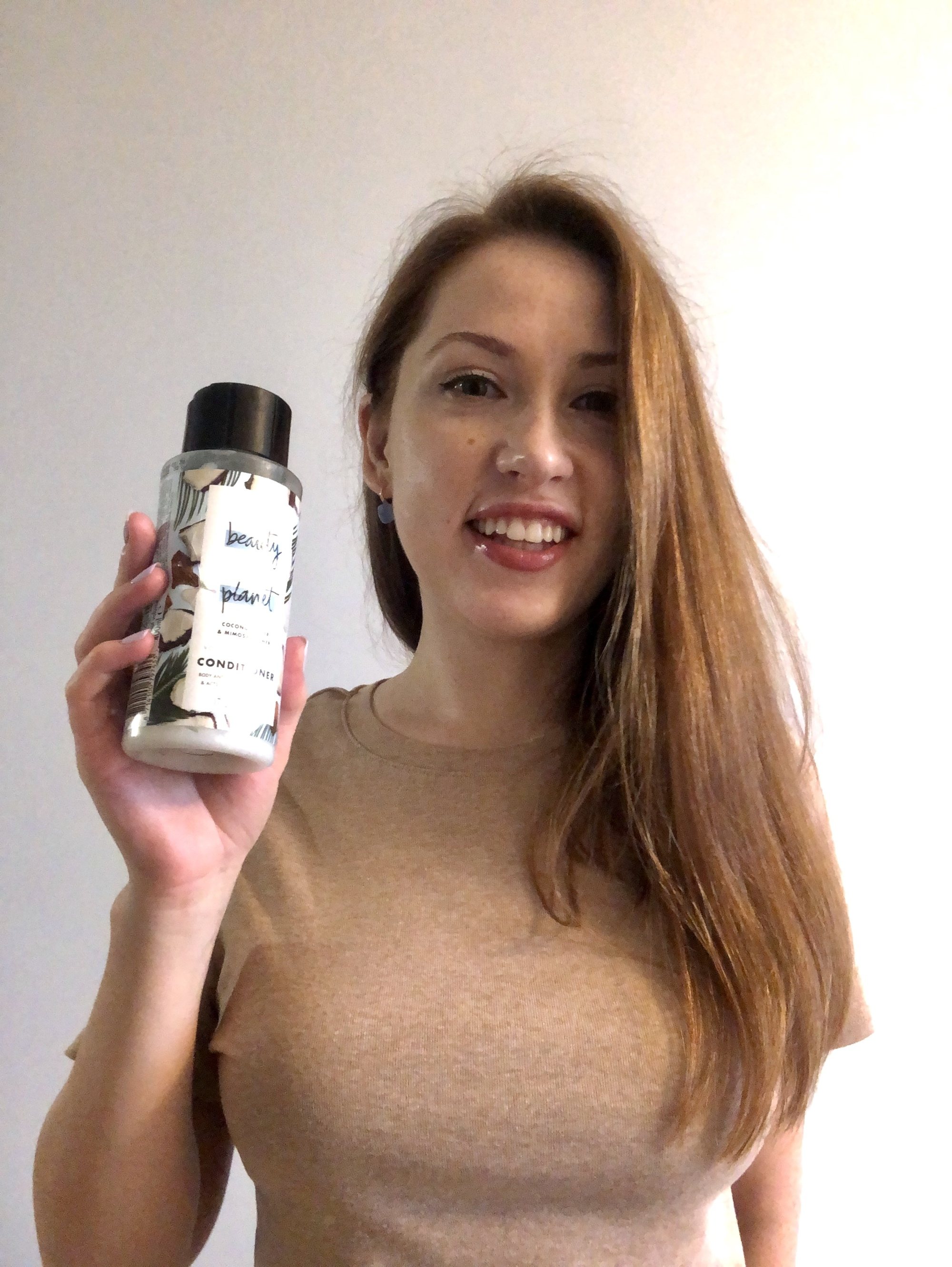 woman with long light brown hair holding a shampoo bottle