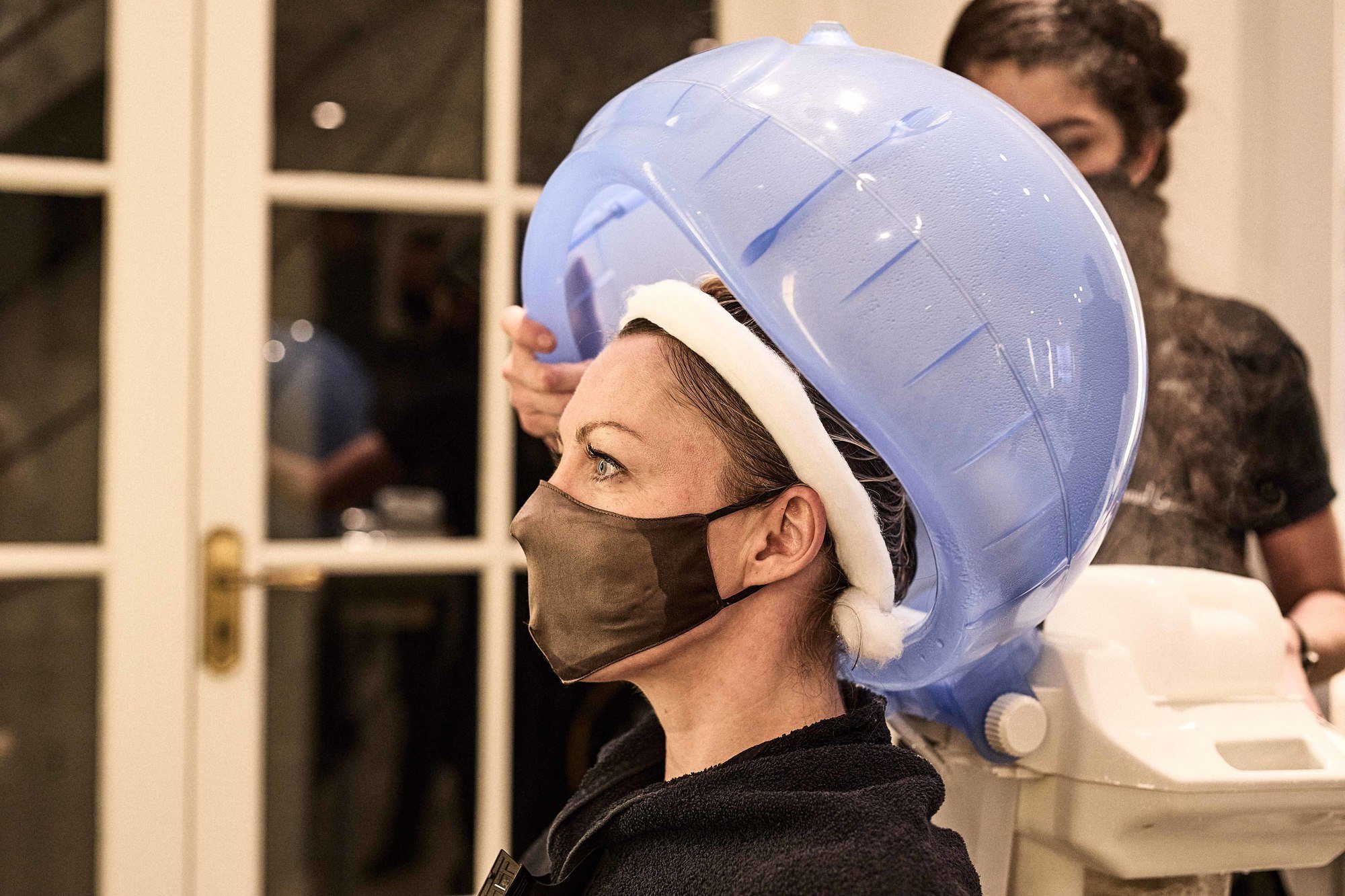 Blonde woman with a hair treatment on under a steamer