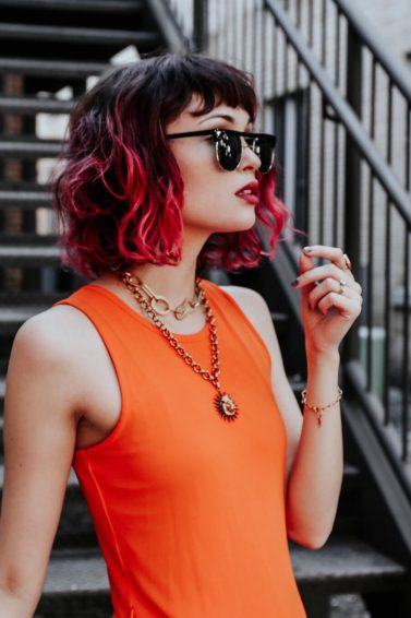 Woman with a black and red ombre wavy bob with a fringe