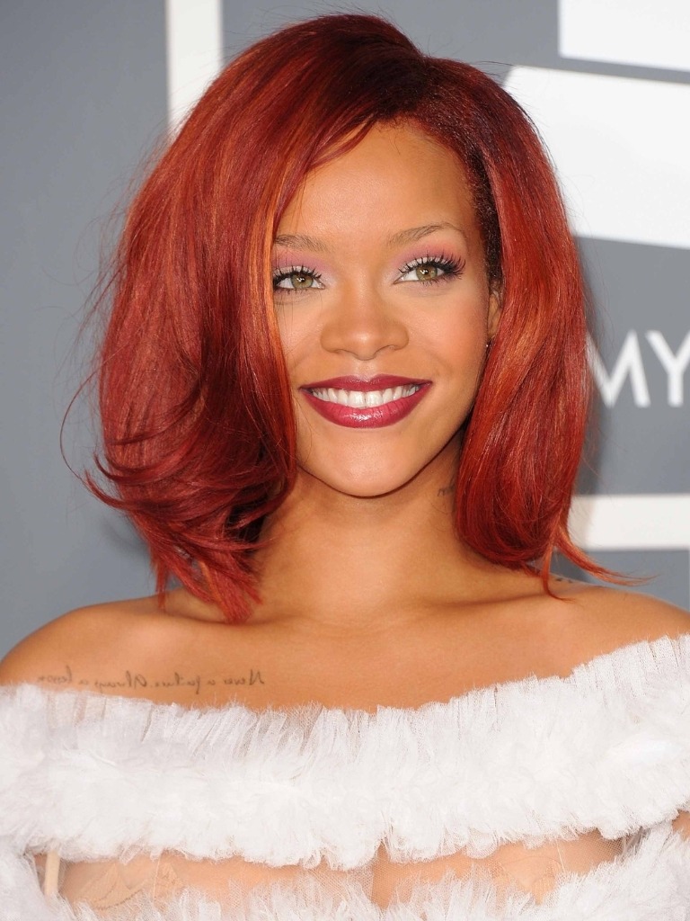Famous redheads: Rihanna with bright red crimson shoulder length hair wearing a fluffy white dress.