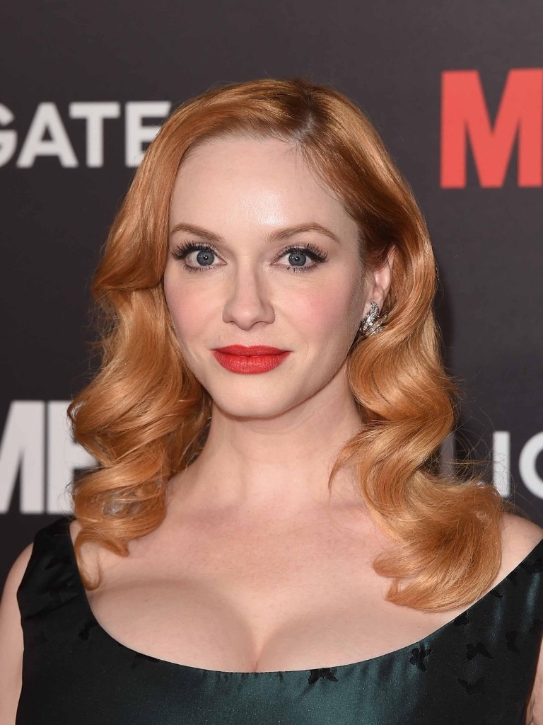 Famous redheads: Christina Hendrick with bright shiny copper ginger wavy medium length hair wearing a dark green dress.