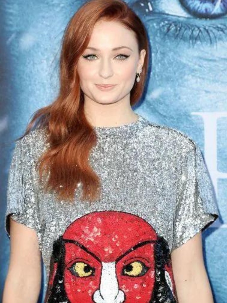Famous redheads: Sophie Turner with long wavy red hair wearing a sparkly tshirt dress.