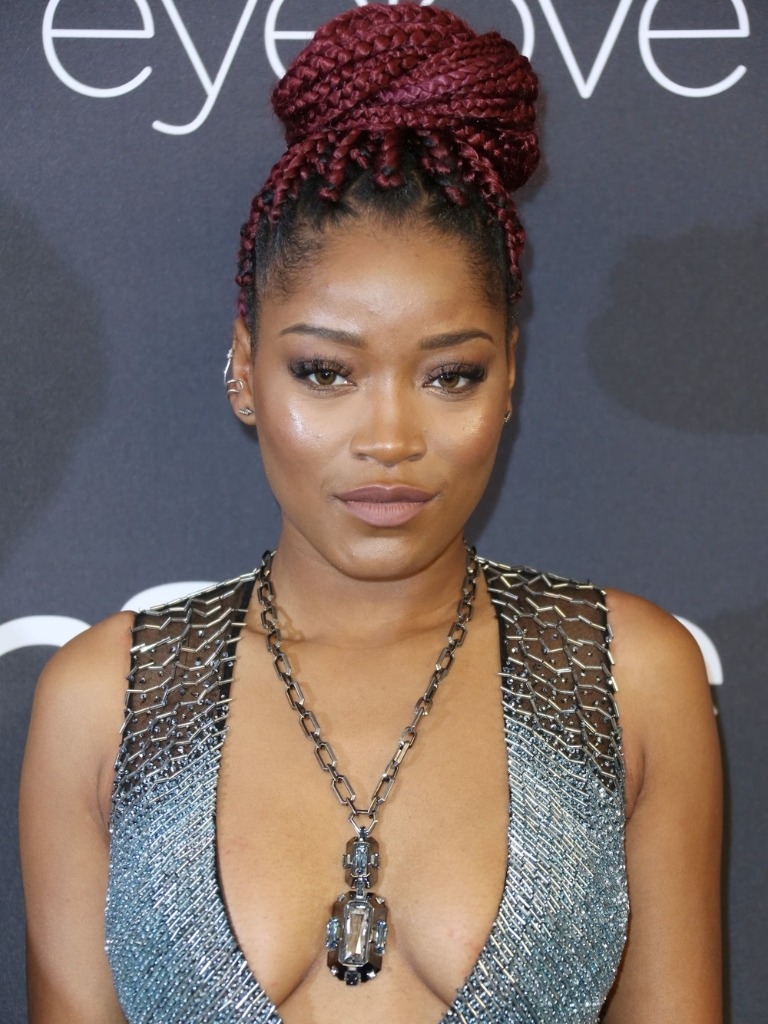 Famous redheads: Keke Palmer with red box braids styled in a high bun updo wearing a silver low cut dress and big necklace.