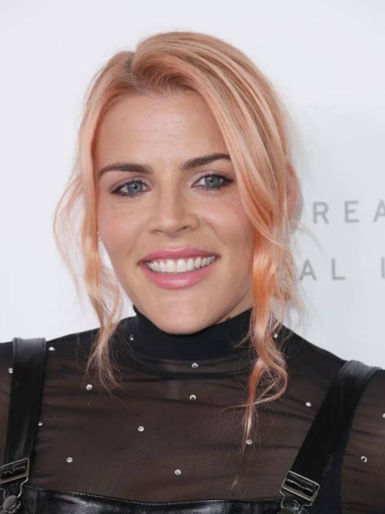 front facing image of Busy Phillips with her hair up and loose sections of pink hair around her face