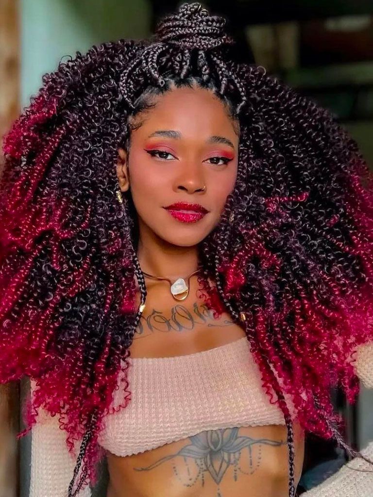 Woman with wild curly hair with red ombre ends plus glossy braids in from, pulled up into a loose topknot
