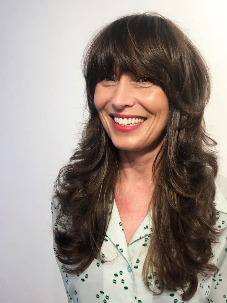 woman with a shaggy long brunette haircut and a heavy rounded fringe