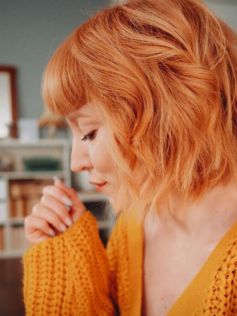 side view of a woman with a bod and peach coloured hair with a fringe