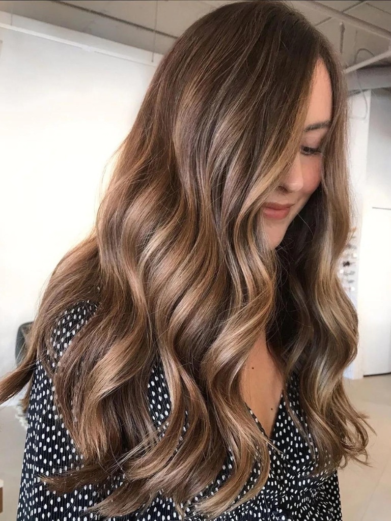 Woman with long wavy warm toned brunette balayage hair
