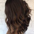 Woman with dark long hair with cocoa brown subtle highlights in her hair