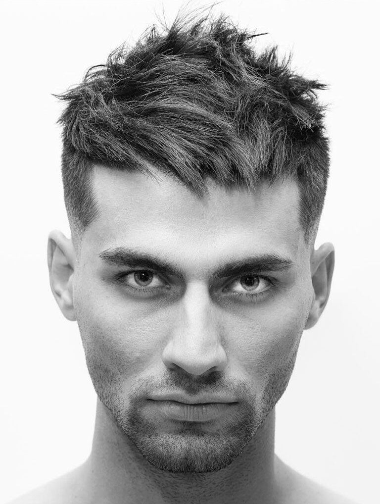 Man with short, razored textured haircut looking straight to camera. Black and white image