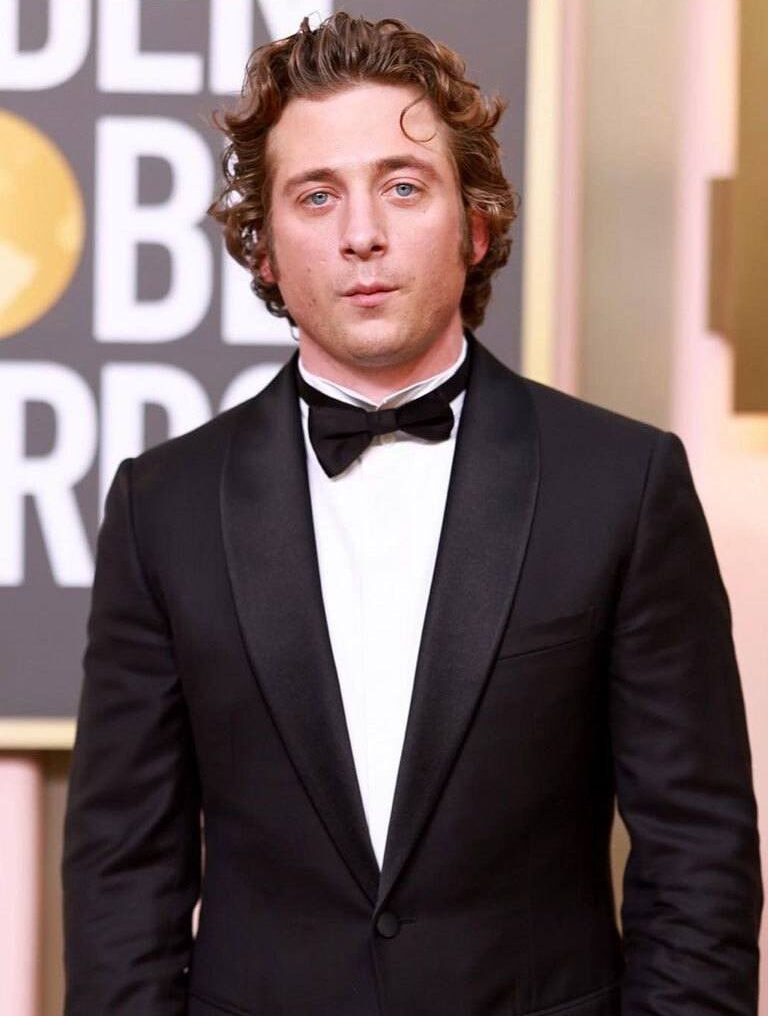 Jeremy-Allen-White at red carpet event sporting a 70s curly hairstyle