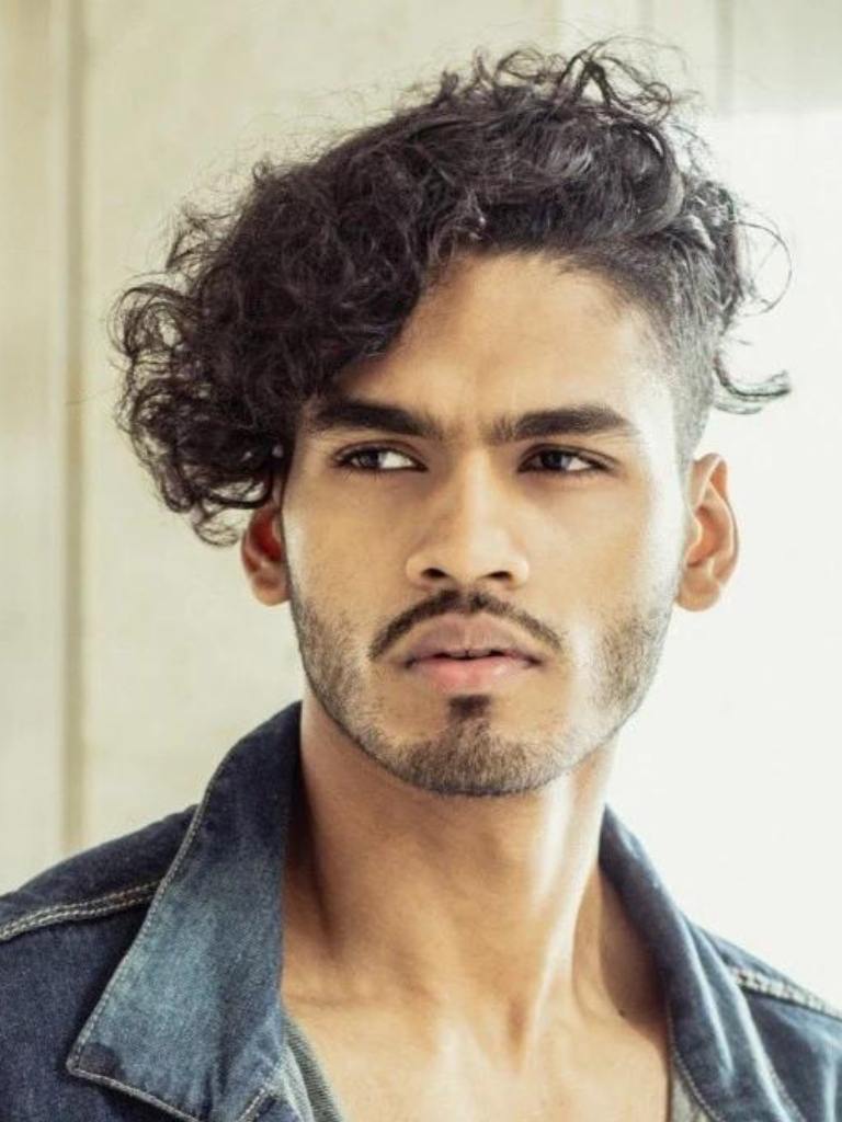 Man with dark brown medium-length curly hair with an undercut