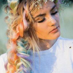 Fishtail braids: Woman with blonde colourful hair with a fishtail hairstyle and flowers in her hair