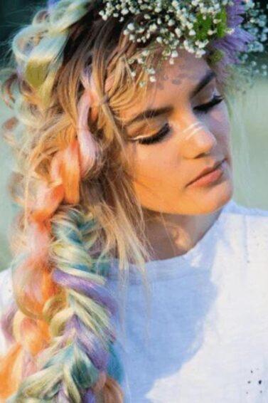 Fishtail braids: Woman with blonde colourful hair with a fishtail hairstyle and flowers in her hair