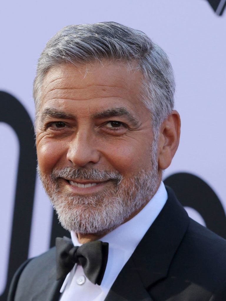 Hairstyles for men over 50: George Clooney with a short tapered combover and grey beard wearing a smart suit.