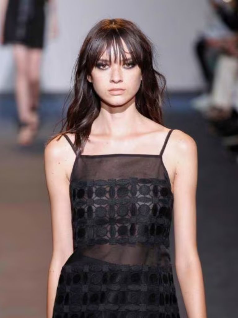 Model on the runway with wispy, '90s style bangs