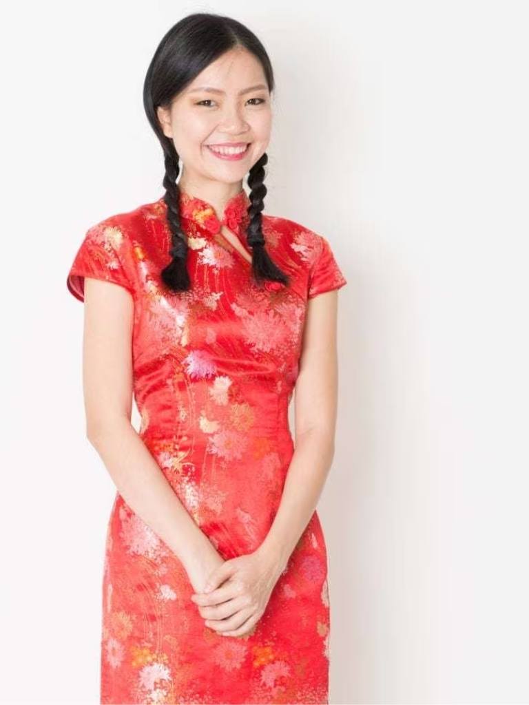 Asian hairstyles: Asian model with brown straight hair in braided pigtails wearing red traditional floral outfit.
