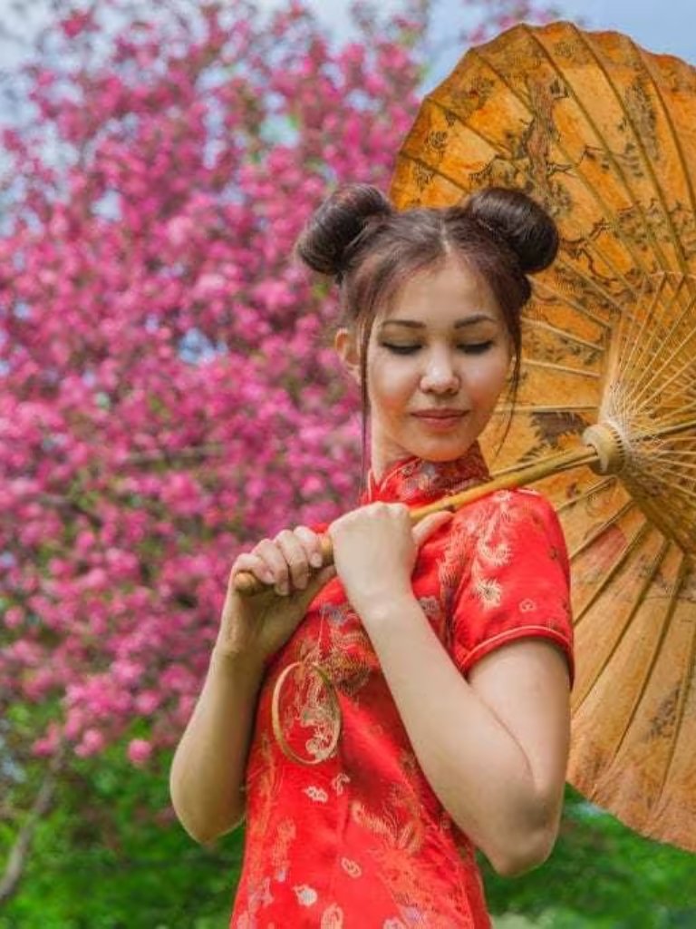 Asian hairstyles: Asian woman with brown straight hair in high donut space buns wearing traditional red outfit.
