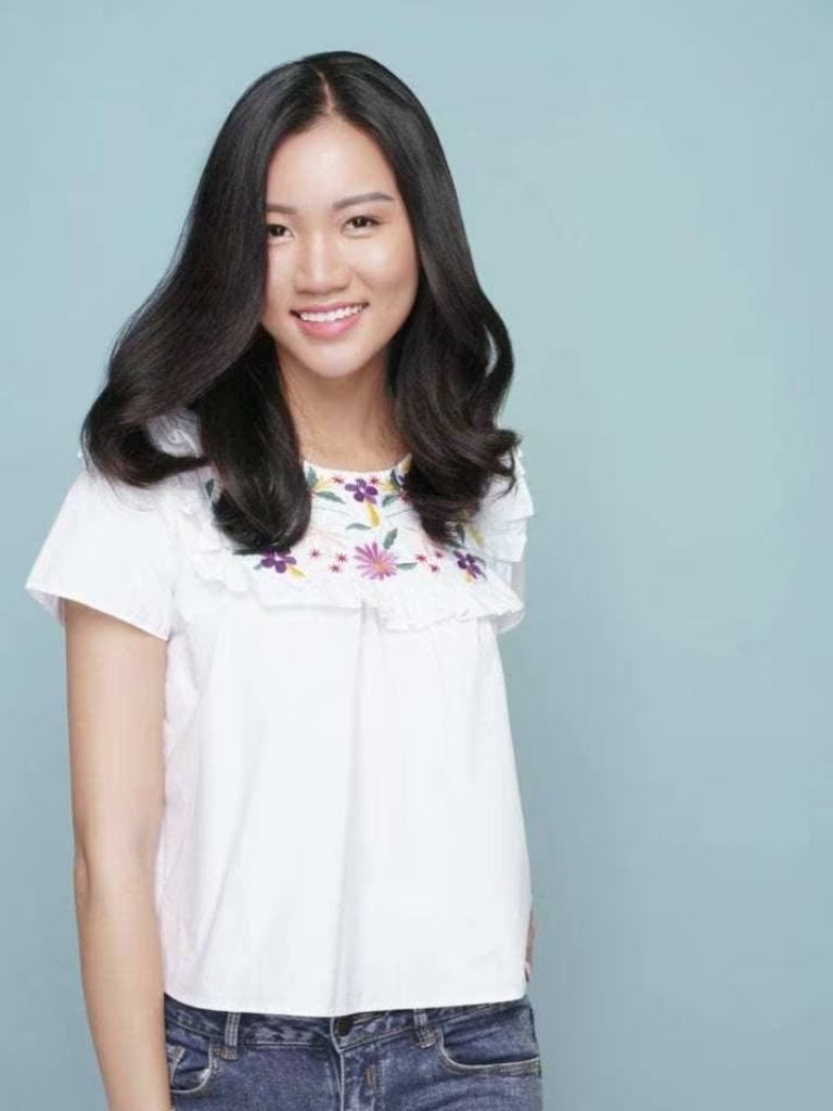 Asian hairstyles: Asian woman with long wavy blowout brown hair wearing a white top and jeans.