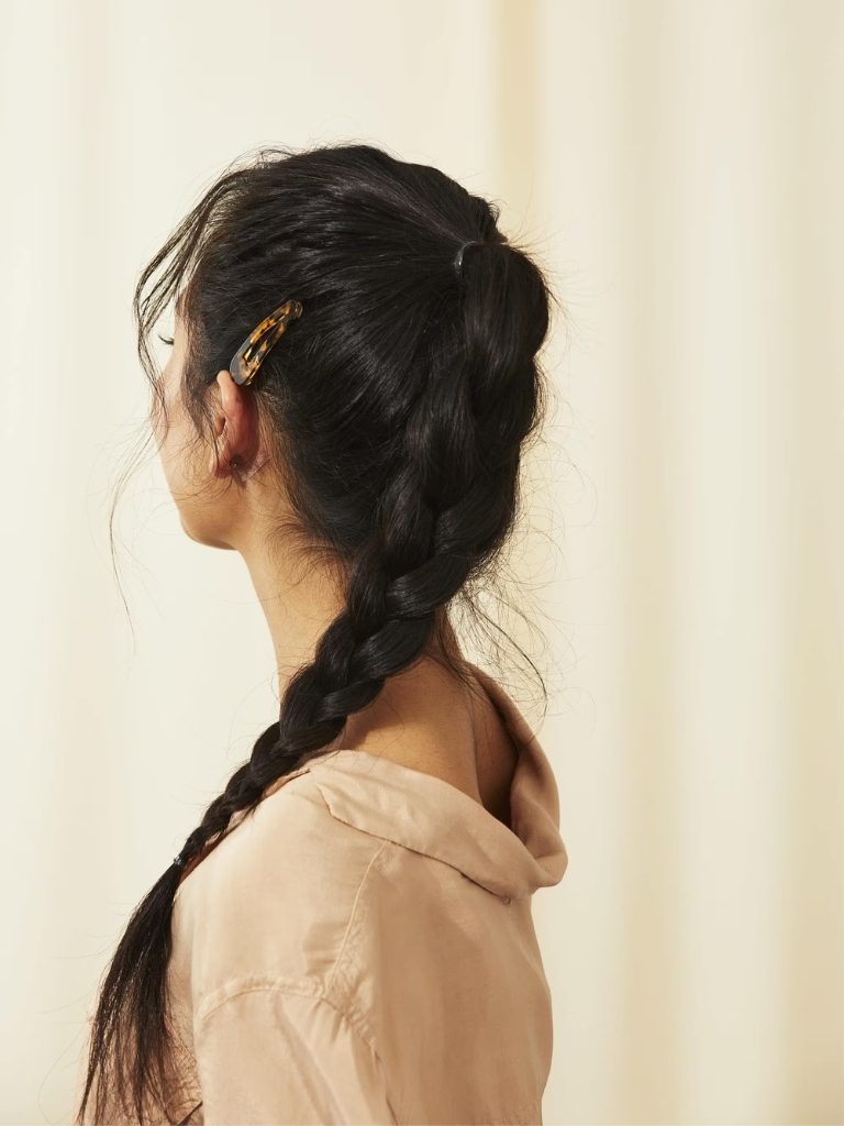 Woman with long braided Asian hair styled into a braided ponytail with hair clip
