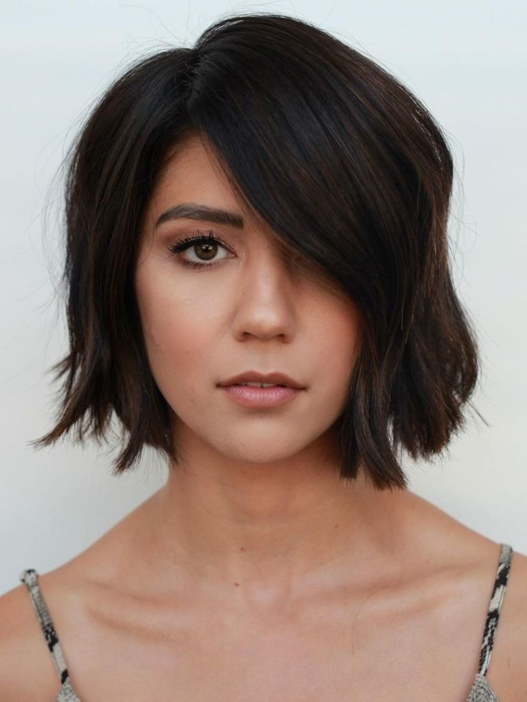 Woman with dark brown long choppy bob with a side parting.