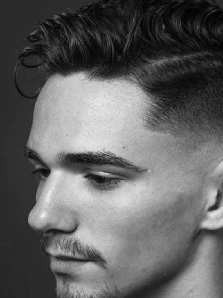 Taper comb over haircut: Black and white photo of a man with a curly taper fade haircut