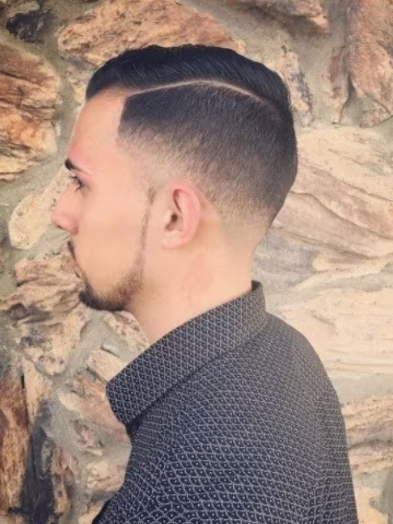 side profile of a brunette guy wearing a smart shirt with a neat taper comb over haircut
