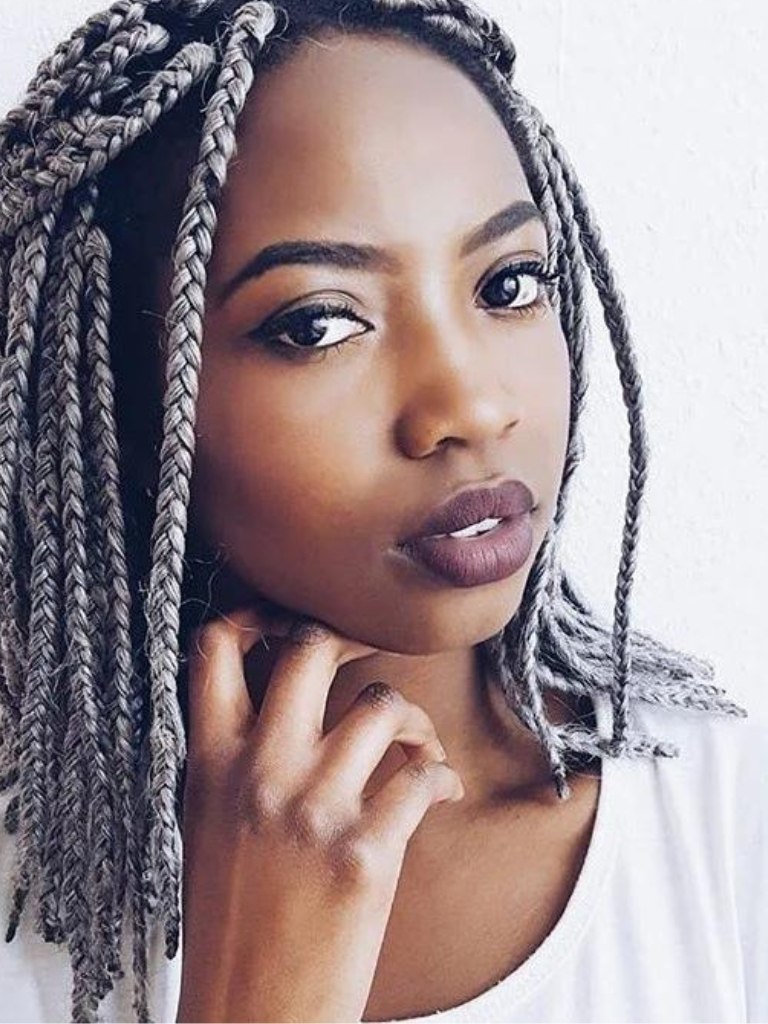 medium box braids: shot of black woman with medium box braid hair styled into a half up and half down style