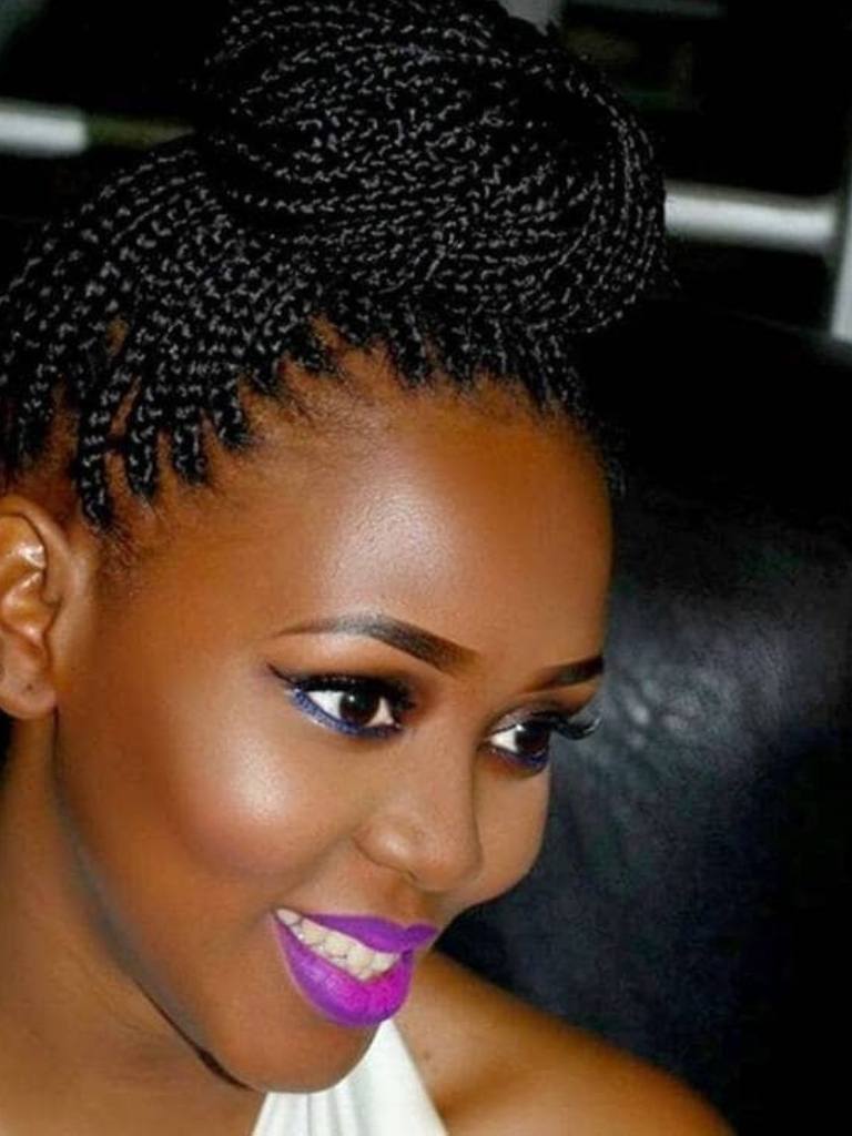 medium box braids hairstyles: woman with high bun hairstyle smiling