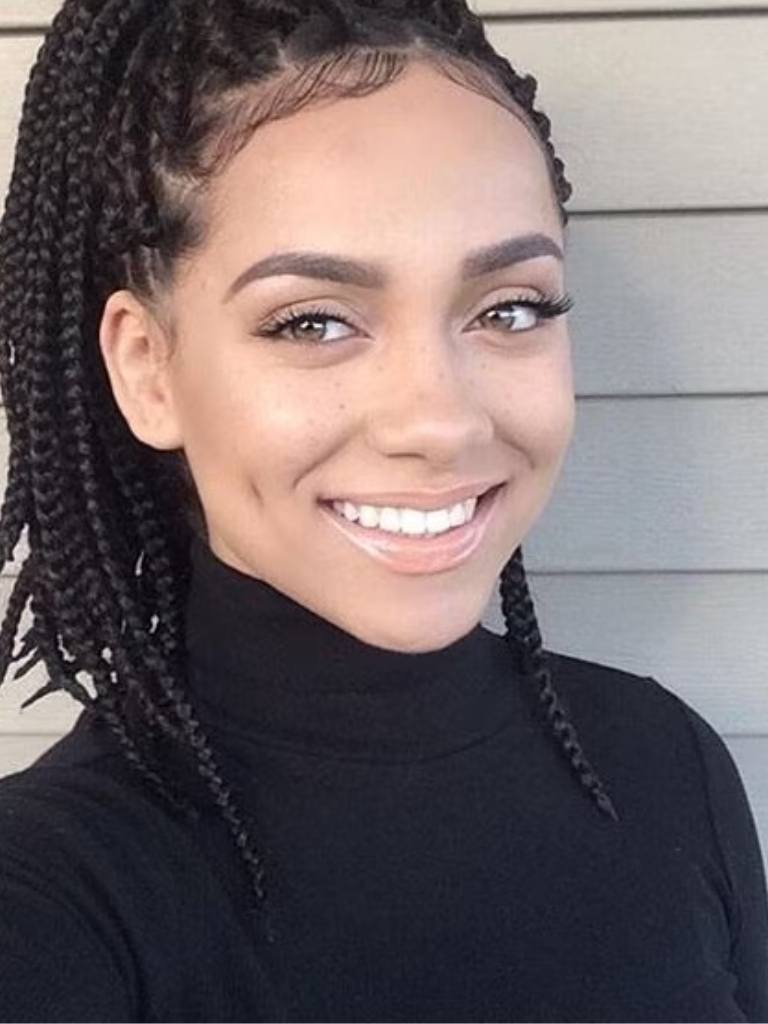 medium box braids styles: shot of woman with medium box braids smiling with her hair styled into a half up ponytail