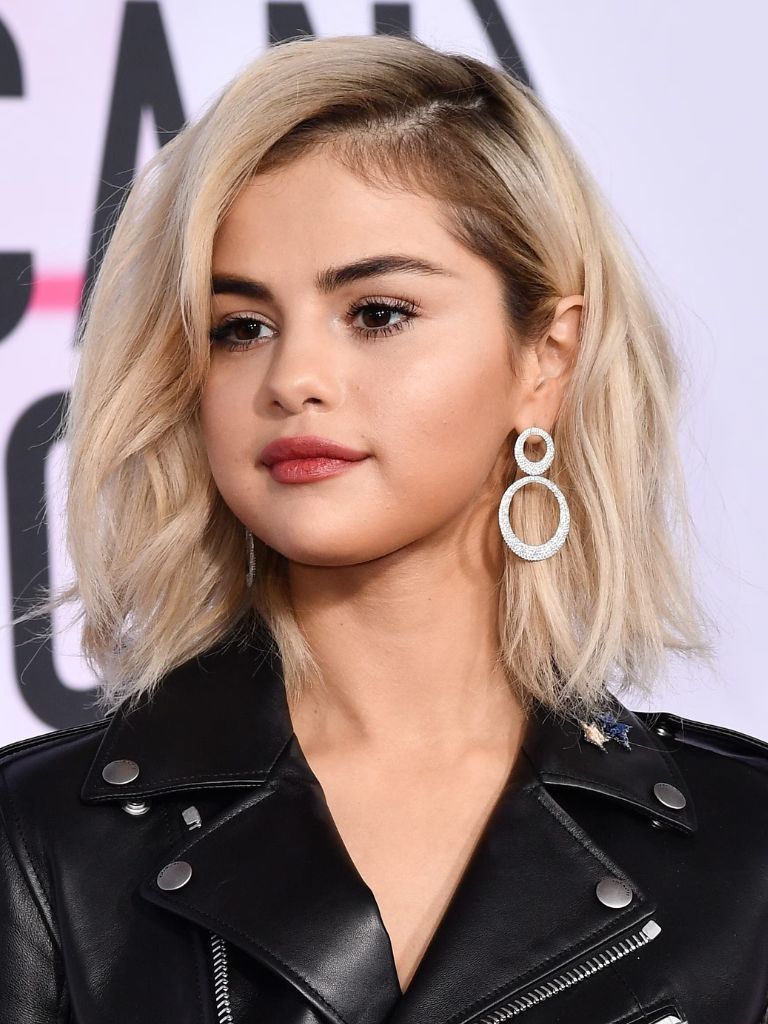 Selena Gomez with bleach blonde long choppy bob and dark roots.
