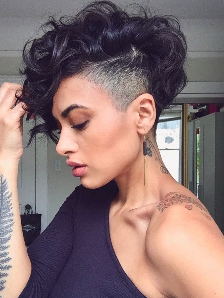 Profile view of woman with tousled thick loose curly hair in a mushroom haircut with severe undercut and fade