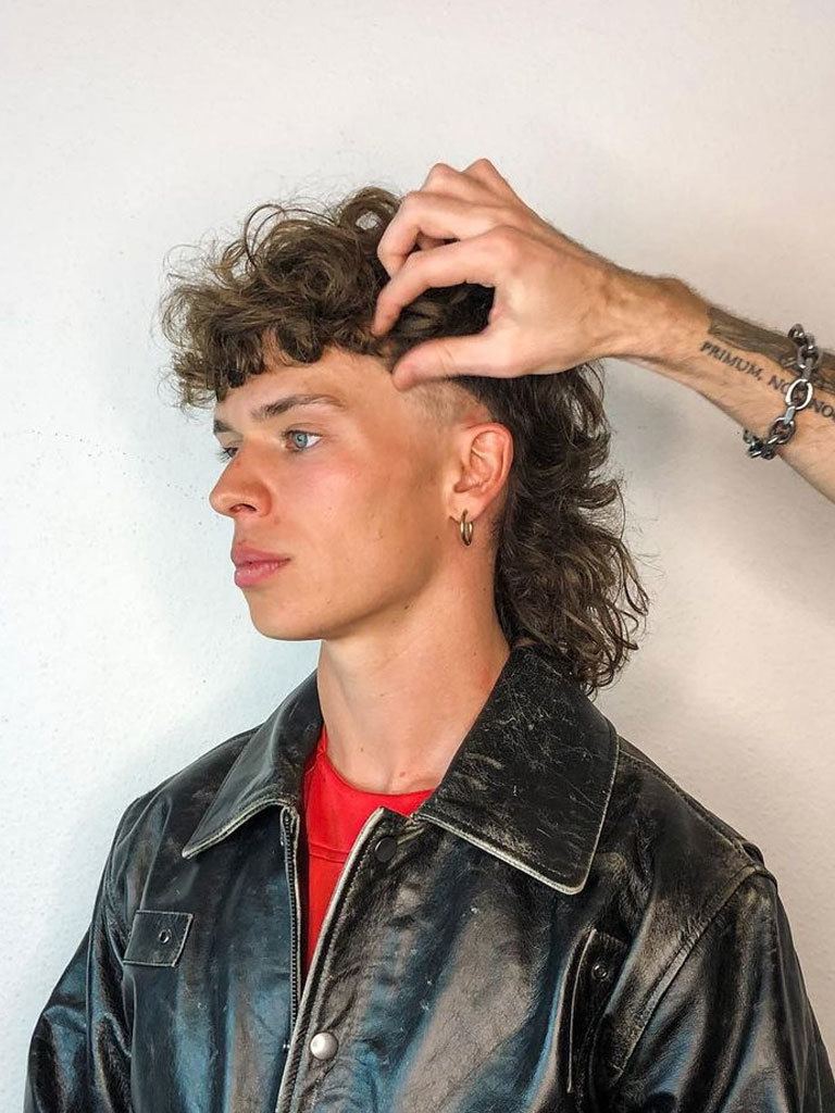 man with a modern mullet men's hairstyle with modern fauxhawk mullet with fade and curly textured top and fringe