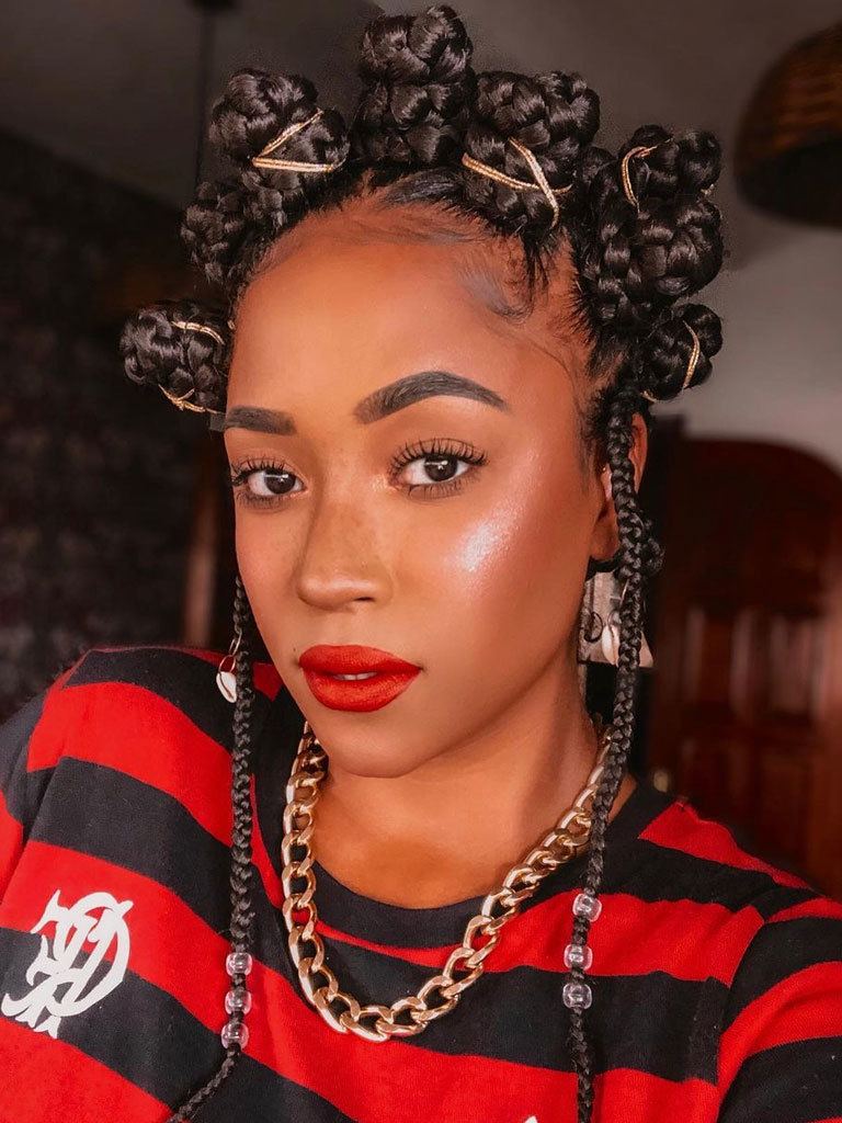 Woman with multiple small space bun box braids wrapped with gold elastics