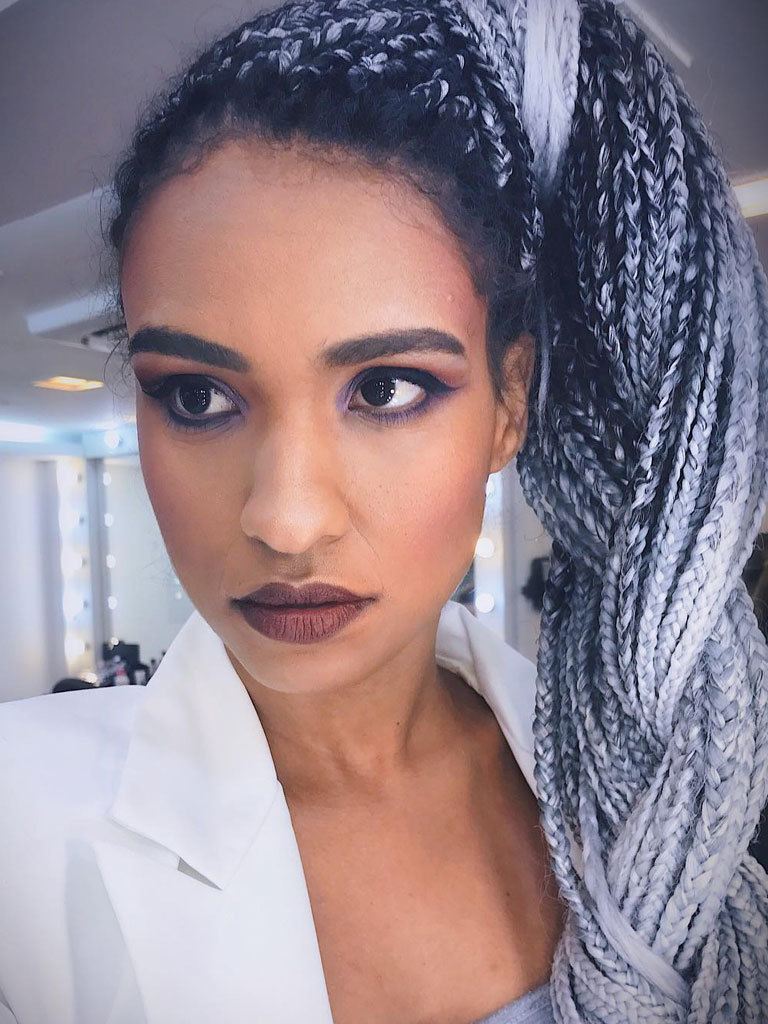 Long box braids hairstyles: woman with grey coloured box braids in a side braid ponytail