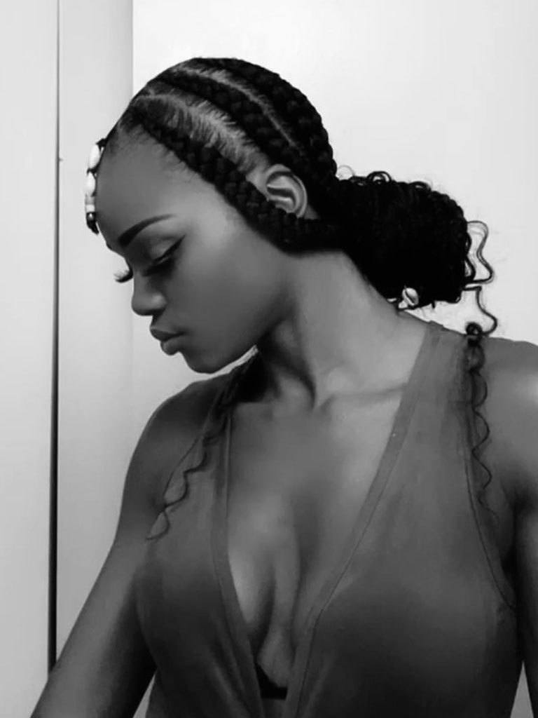 Black and white pic of a woman in side profile with thick feed-in box braids swept into a low pony that's been half tucked into a bun