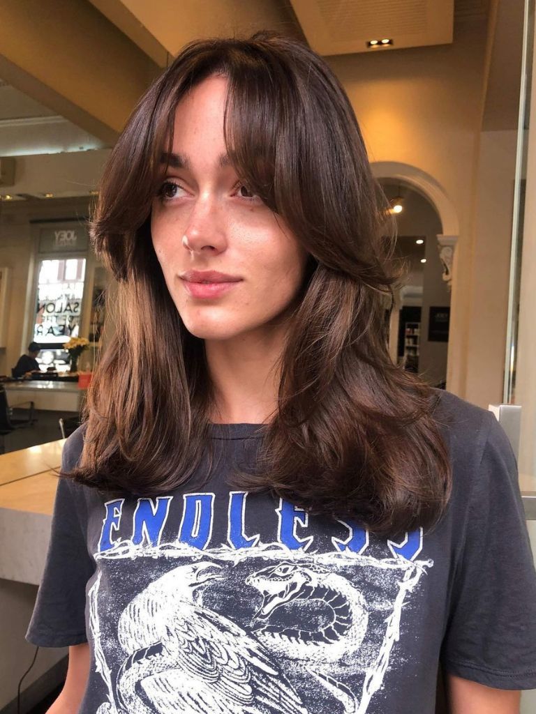 woman with long brunette hair and sweeping curtain bangs