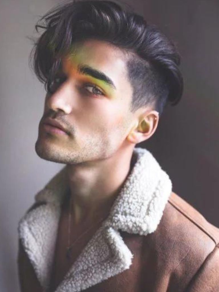 brunette man in a tan shearling jacket with floppy hair and an undercut