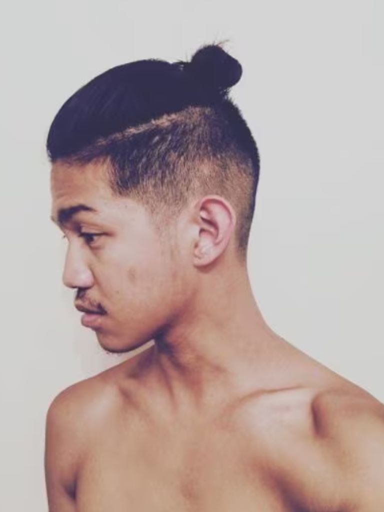 side profile of an asian man with a samurai style top knot and undercut