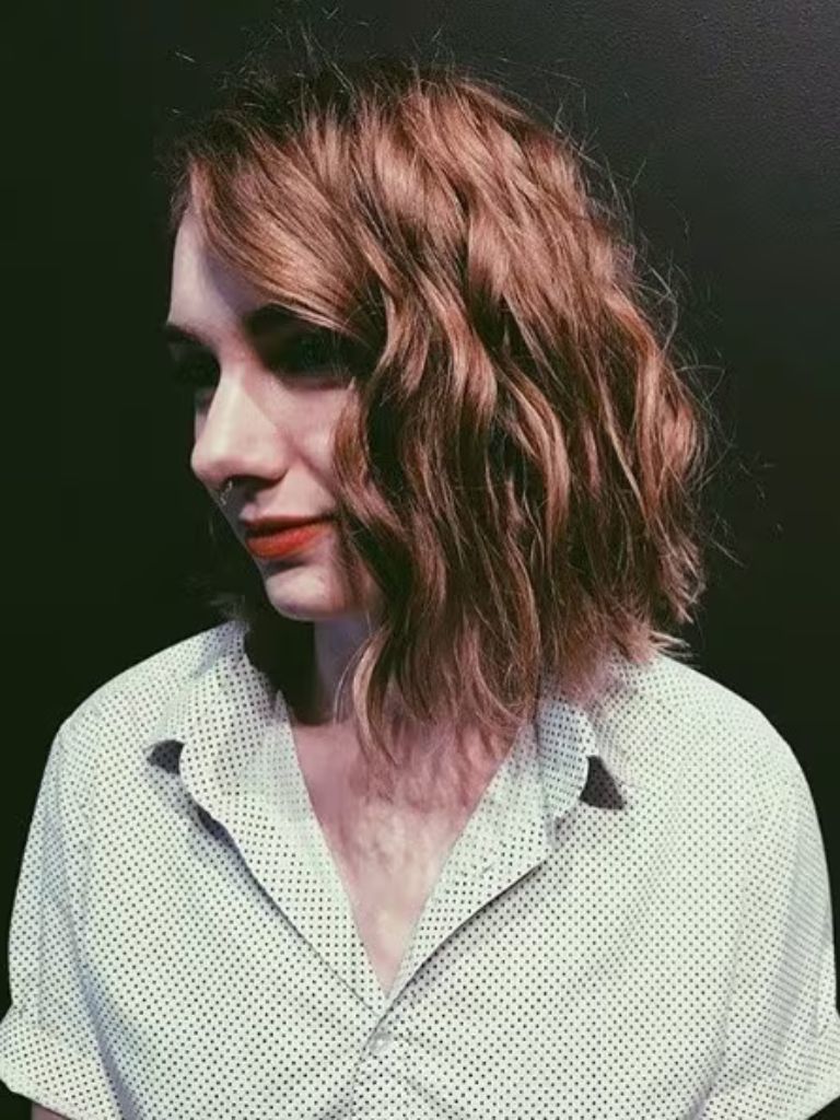 Woman with a copper wavy permed graduated bob