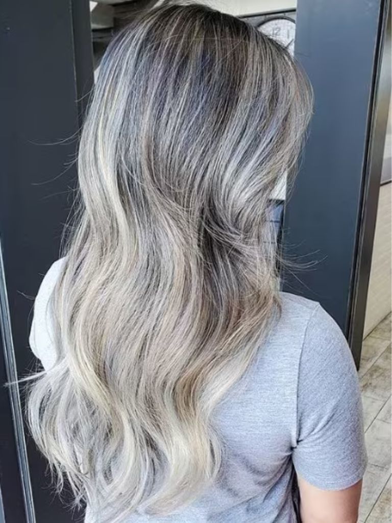 Back view of a woman with smoky grey ash blonde wavy hair, wearing a grey t-shirt