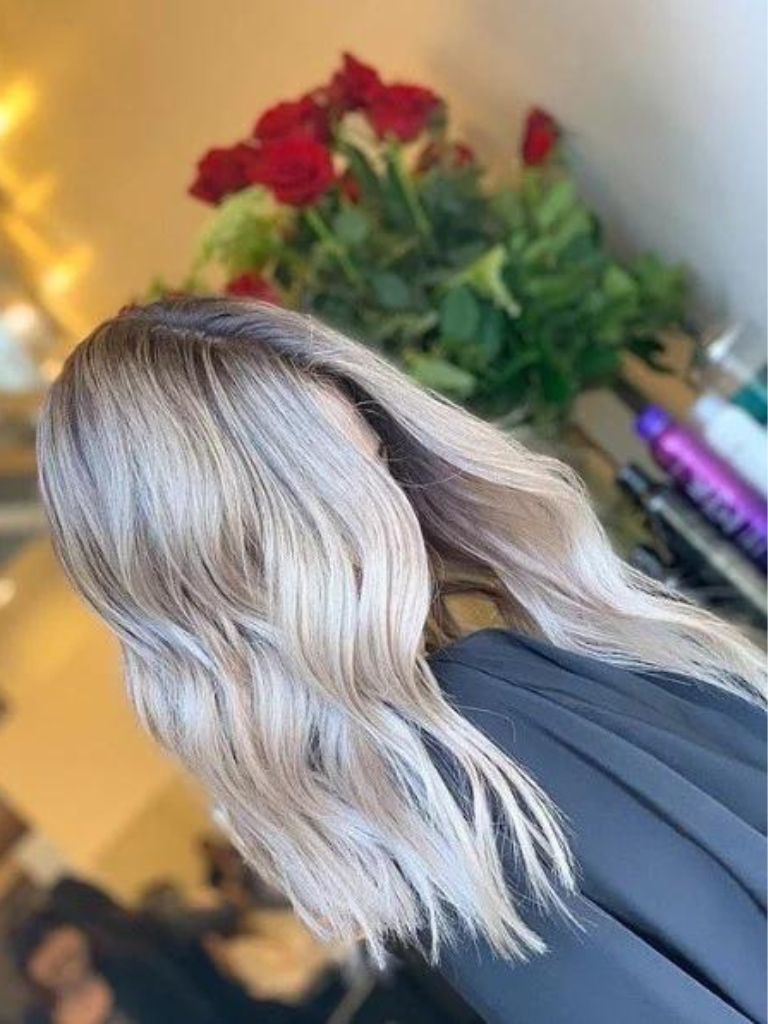 Photo of a woman with shoulder length, wavy light ash blonde ombre hair in a salon